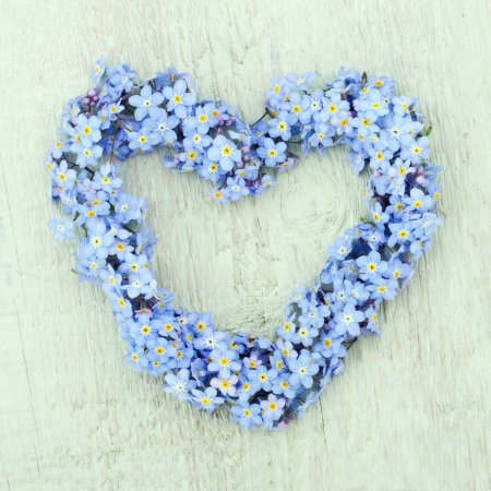 Heart shaped flower wreath of forget-me-not on green wooden backgroundの写真素材