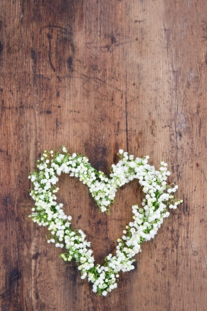 Heart shaped flower wreath of lilys of the valley on rustic wooden backgroundの写真素材