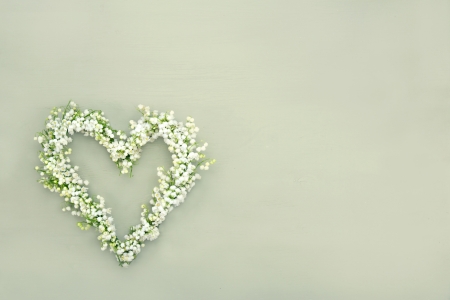 Heart shaped flower wreath of lilys of valley on green wooden backgroundの写真素材