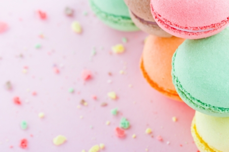 Pile of colorful macaroons on pastel pink background with small crumbsの写真素材