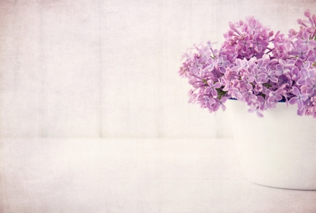 White vase with a bouquet of purple lilac spring flowers on vintage textured backgroundの写真素材
