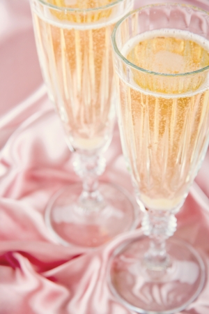 Two glasses of champange or sparkling wine on pink satin backgroundの写真素材