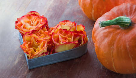 Orange halloween pumpkin and flowers with heart shape on red wooden rustic backgroundの写真素材