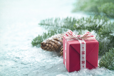 Pine cones, Xmas present and green spruce tree branches with snow in a decorative rustic Christmas...