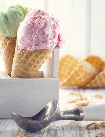 Pink and green ice cream cones with an old metal scoop on wooden rustic backgroundの写真素材