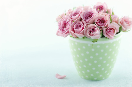 Romantic bouquet of roses in green cup on blue vintage background with textured editingの写真素材