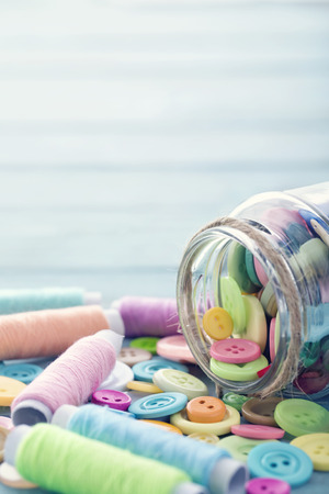 Multicolored buttons and spools of thread on light blue background - sewing conceptの写真素材