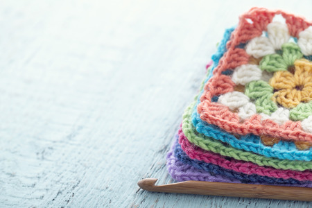 Pile of colorful crochet granny squares on light blue wooden vintage backgroundの写真素材