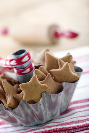 Homemade Christmas gingerbread cookies in a rustic metal cup on red vintage backgroundの写真素材