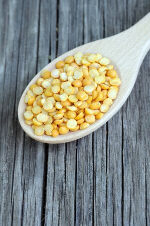 yellow split pea in wooden spoon on grunge tableの写真素材