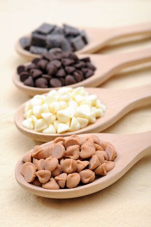 four kinds of chocolate chips in wooden spoonsの写真素材