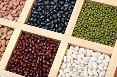 black, mung, white, and light red beans in wooden trayの写真素材