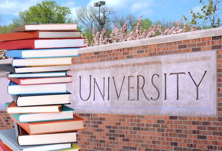 a pile of books in front of universityの写真素材