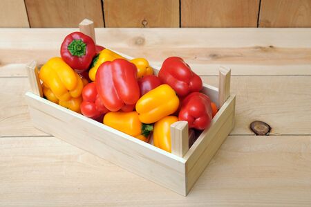 colorful bell peppers in crate on wooden backgroundの写真素材