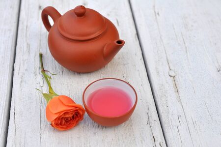 teapot and rose on table in gardenの写真素材