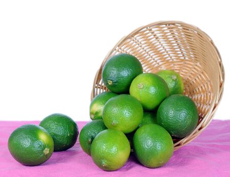 fresh green lime fall out of basket on tableの写真素材