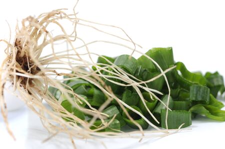 sliced fresh onion leaf and roots on white 