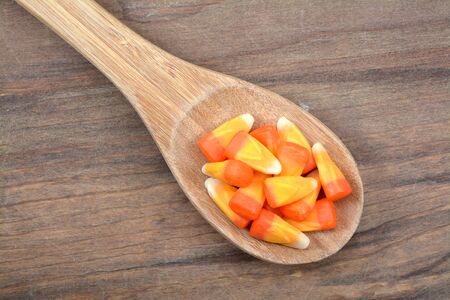candy corn in spoon on rustic wooden table