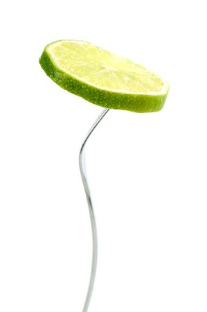 single slice lime in fork isolated on whiteの写真素材