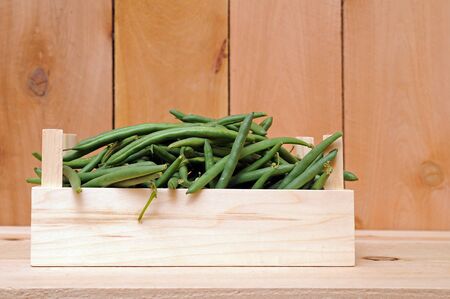 a lot of green beans in crate on wooden shelfの写真素材