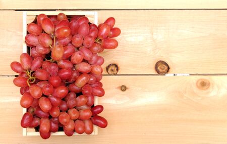 a bunch of red grape in case on wooden tableの写真素材