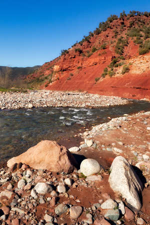 Ourika valley mountain river with rocks at front and hills at backの写真素材