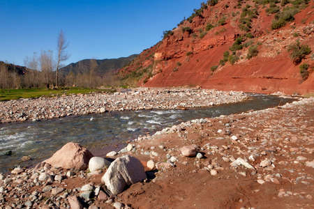 Ourika valley mountain river with rocks at front and hills at backの写真素材