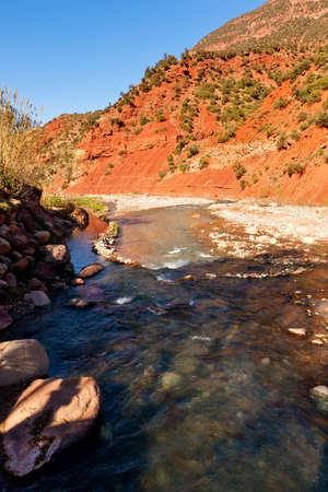 Ourika valley mountain river with rocks at front and hills at backの写真素材