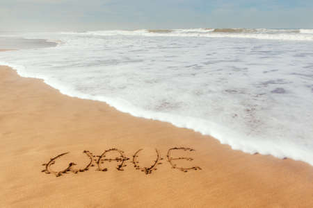 Single word wave written on sand with ocean waves flowingの写真素材