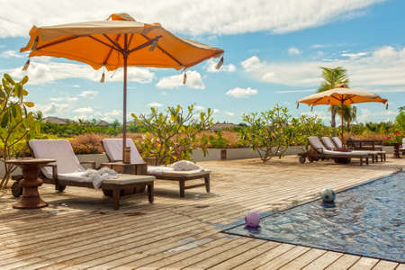 Beach Lounge Chairs with towels under umbrella at the poolside of the hotel, Zanzibar, Tanzania