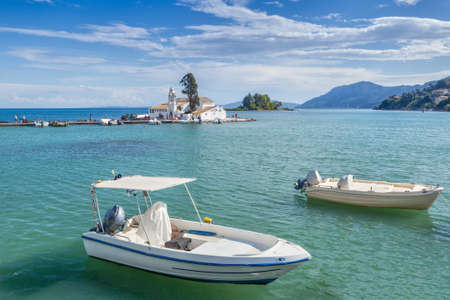Traditional greek fishing boats with famous touristic landmark Monastery of Panagia Vlahernon at background, Kerkyra, Corfu, Greeceの写真素材