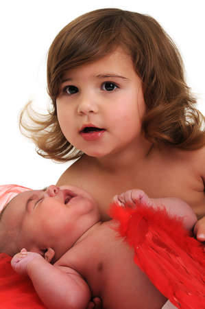 two sisters playing and smiling in studio wearing red angle wingsの写真素材