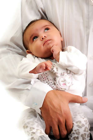 baby looking up at her father while been held in his armsの写真素材