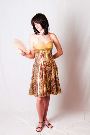 sexy image of beautiful young brunette model holding a white with Chinese hand fan in her hand while standingの写真素材
