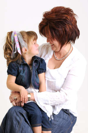 young daughter kissing mother on the cheek and smilingの写真素材
