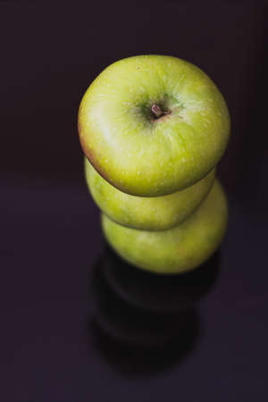 Green balanced apples stack reflecting on black backgroundの写真素材