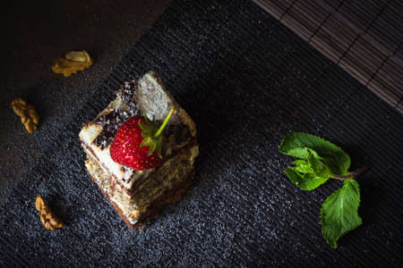 Piece of poppy seed cake with strawberry and mint on the table covered with bamboo runner rugの写真素材