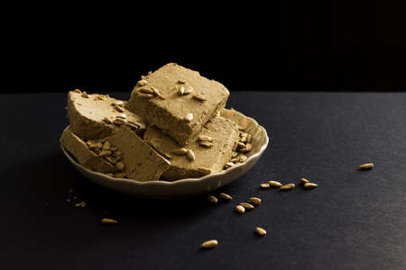 Sunflower halva with seeds on plate on black backgroundの写真素材