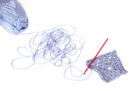 Light blue skein of acrylic thread with the unwound string, square crochet element and red hook isolated on whiteの写真素材
