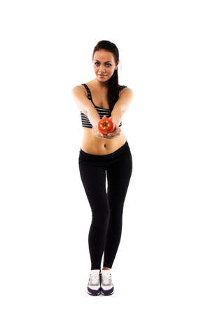 Slim girl wearing training suit offering a tomato, isolated on white, healthy life-style promotionの写真素材