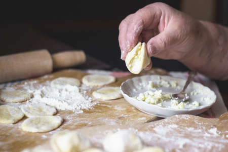 Old woman's hands cooking Ukrainian traditional dumplings with cottage cheeseの写真素材