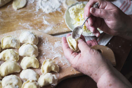 Old woman stuffing Ukrainian traditional dumplings with cottage cheeseの写真素材
