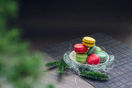 Winter still life with traditional French macaroons on the small plate and fir tree branches. Space for your text on the top of the imageの写真素材
