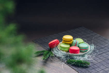Winter still life with traditional French macaroons on the small plate and fir tree branches. Space for your text on the top of the imageの写真素材