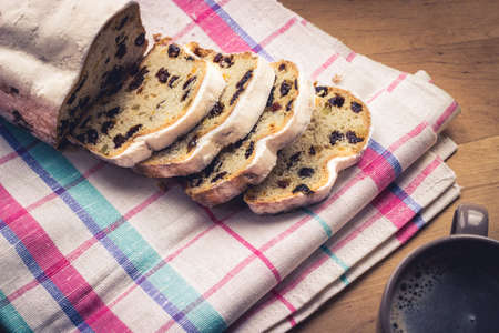 Stollen, traditional German Christmas yeast cake with raisins served with a cup of coffee, decorated...