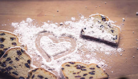 Stollen, traditional German Christmas yeast cake with raisins on wooden table, heart drawn on sugar powderの写真素材