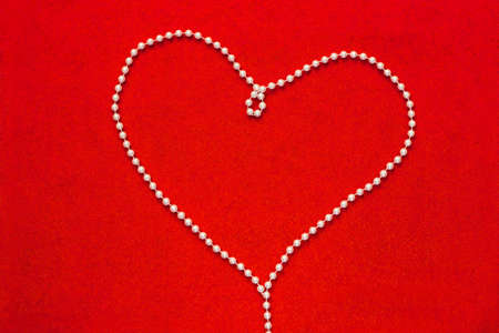 Pearl beads in Heart shape on the red felt background. Love conceptの写真素材