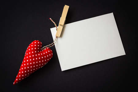 Blank white paper card for copy space and vintage handmaded red valentines day toy heart over black backgroundの写真素材