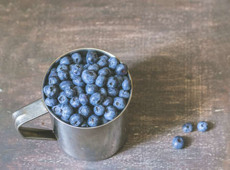 Blueberries in metal mug on wooden backgroundの写真素材