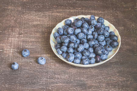 Blueberries on white plate on wooden backgroundの写真素材